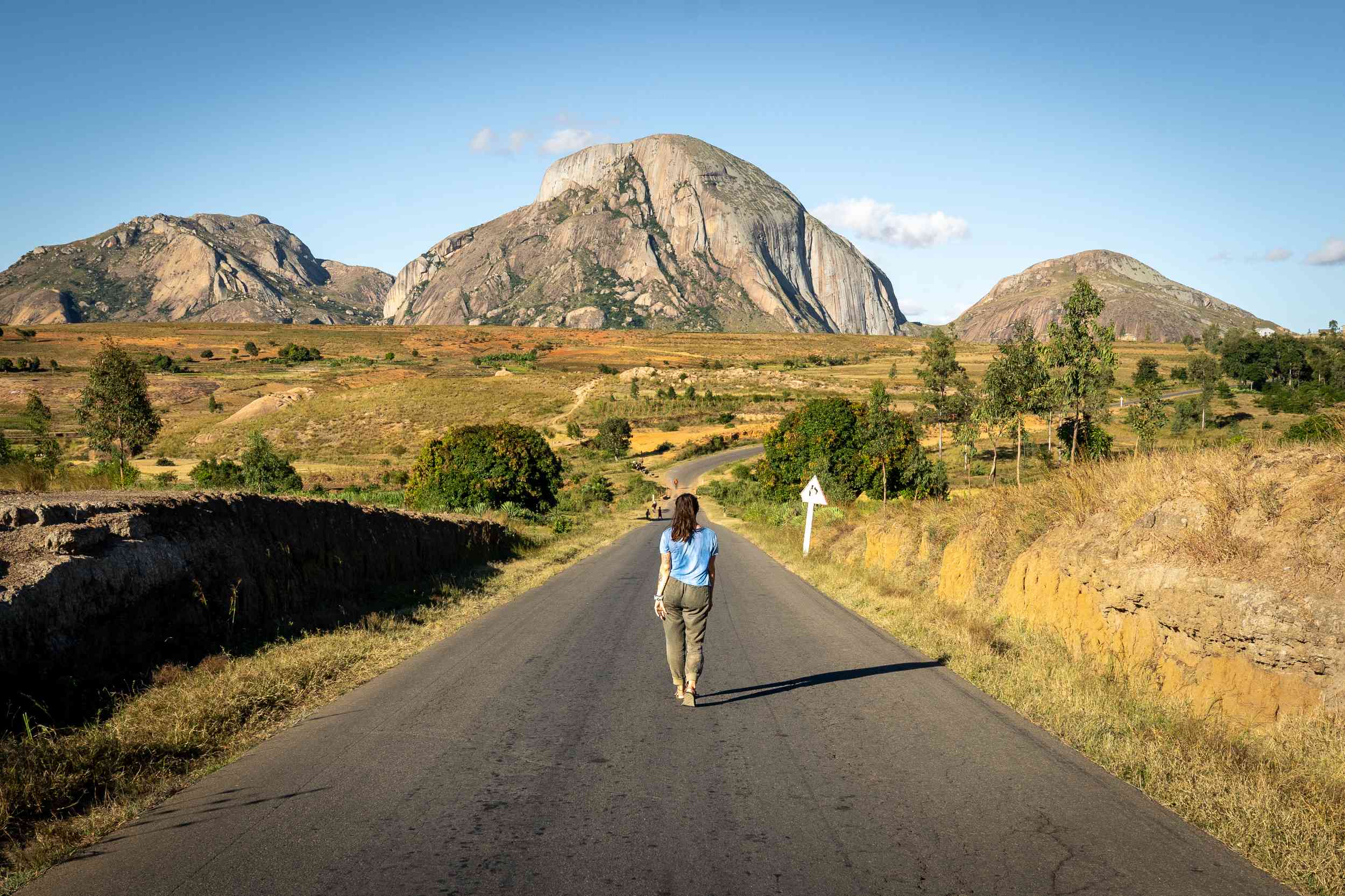 Woman walking along a road facing the mountains